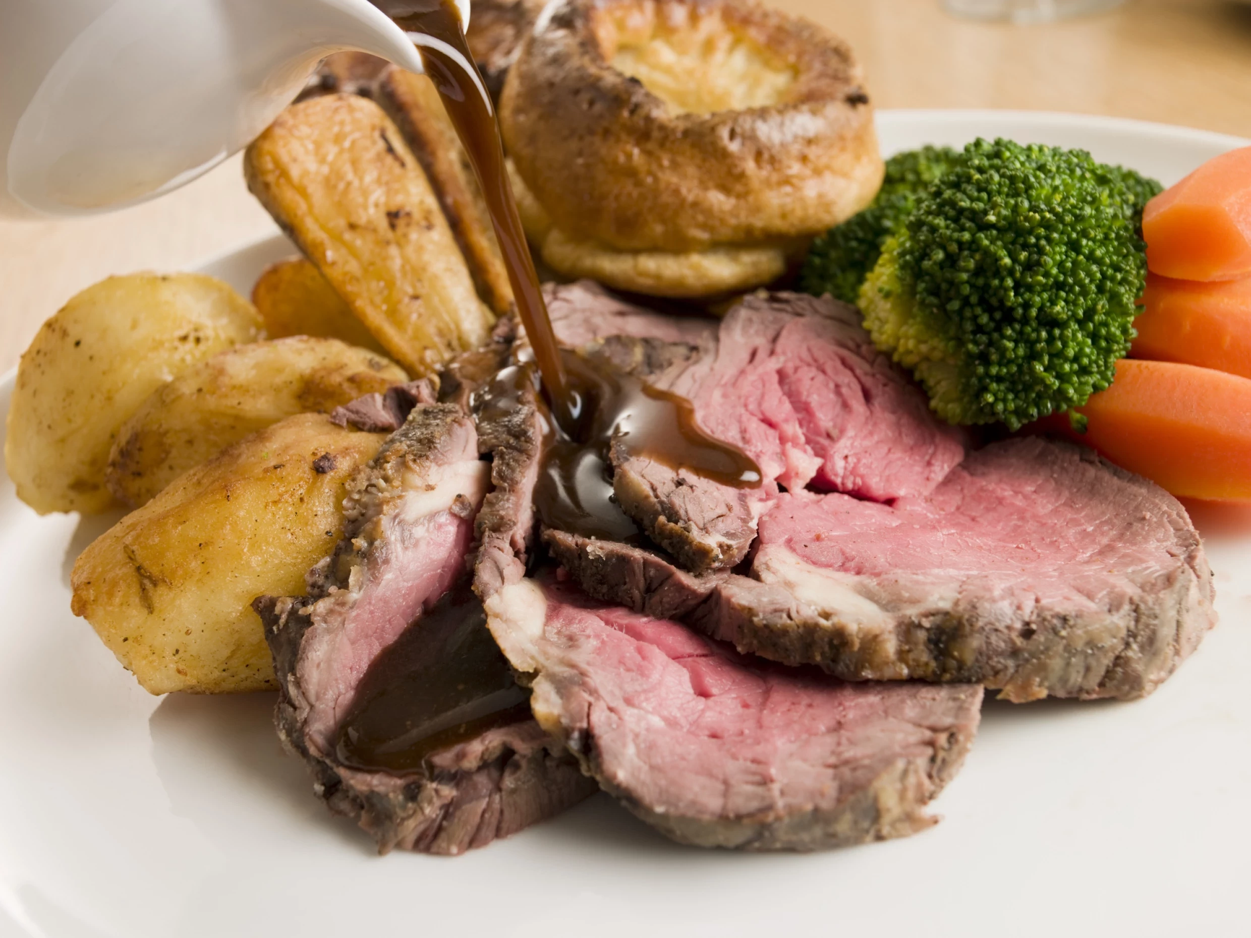 Gravy being poured over a juicy, medium-rare beef fillet