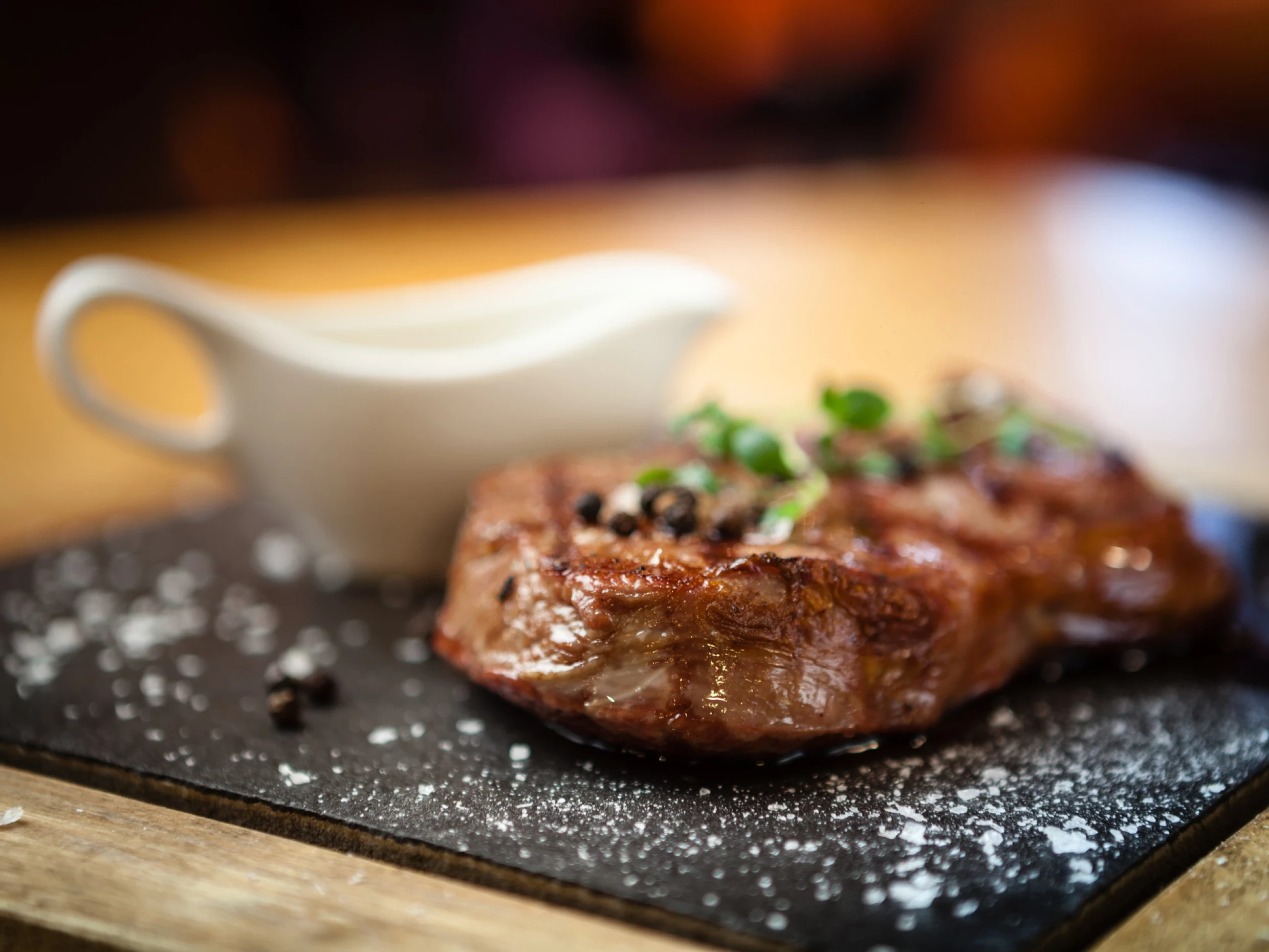 new york steak on a stone plate with cracked pepper and corriander on top.